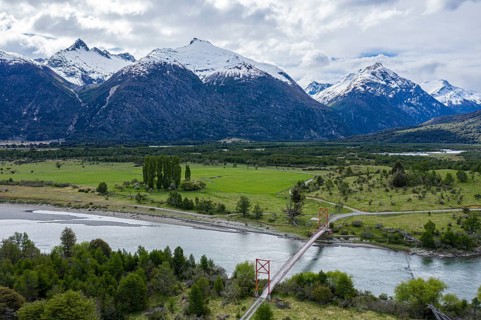 Old-style suspension bridge over river Rio Nadis south of Cochrane, snow-capped mountains at Rio