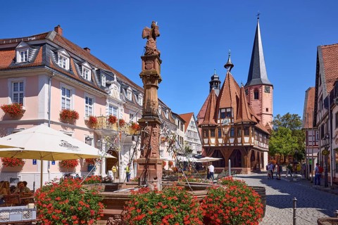 Market fountain with blooming geraniums and historic town hall on the market square under a