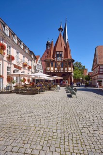 Historic town hall with outdoor area of the confectionery and café Leyhausen under a cloudless blue