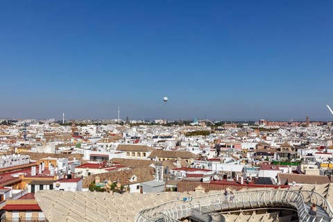 Sweeping views over the city with a hot air balloon on the horizon under a clear blue sky, Seville