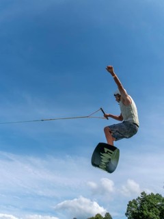 Young man jumping and flying with wakeboard, water sports and water skiing in the wakepark