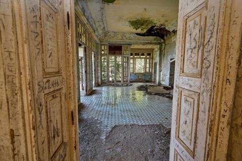 Abandoned building with large windows and dirty tiles, the dilapidated interior has clear signs of