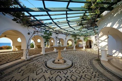 A bright, Mediterranean-inspired courtyard with cobblestones and climbing plants, overlooking the