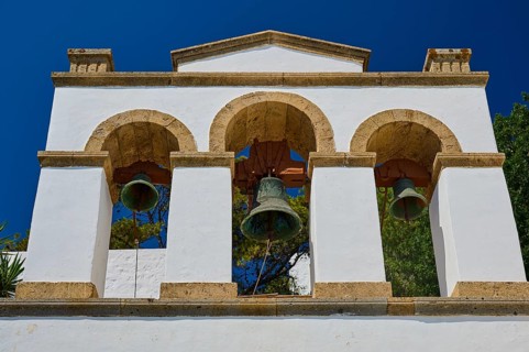 Cross-domed church of Diasososuan, white bell tower with three arches and hanging bells against a