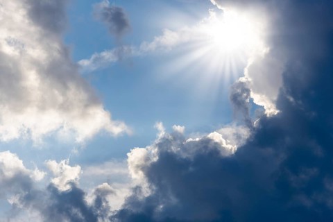 Rain clouds with sun shining through, rays of sunshine, blue sky