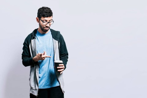 Person holding and pointing coffee on isolated background. Guy pointing disposable cup of coffee