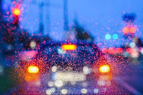Blurred view of car lights at night through rain-soaked windows