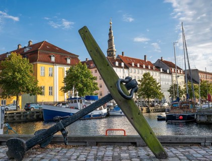 Old anchor, sailing boats, historic buildings and tower of Vor Frelsers Kirke or Church of the