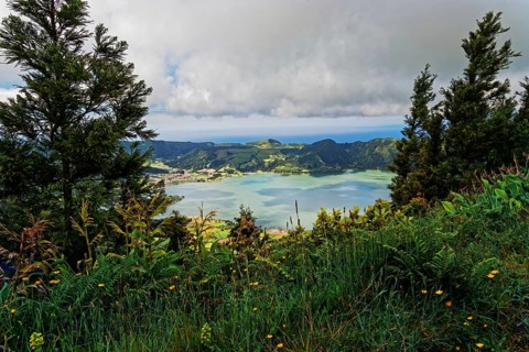Fascinating view of the crater lake Lagoa Azul with wild flowers in the foreground, Lagoa Azul,