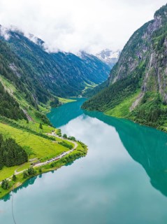 A mirror-like mountain lake nestled in a green, mountainous landscape, Stilluptal, Austria,