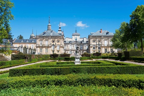 Baroque palace with manicured hedges and sculptures against a clear blue sky, Royal Castle La