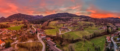 Panoramic view of a village in a hilly landscape at sunset with a red-coloured sky, Bad Feilnbach