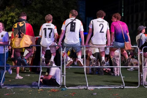 Fans with shirts of the German national team sit on barriers at the fan zone at the Brandenburg Tor