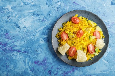 Fried pomelo with tomatoes and avocado on blue concrete background. Top view, copy space, myanmar