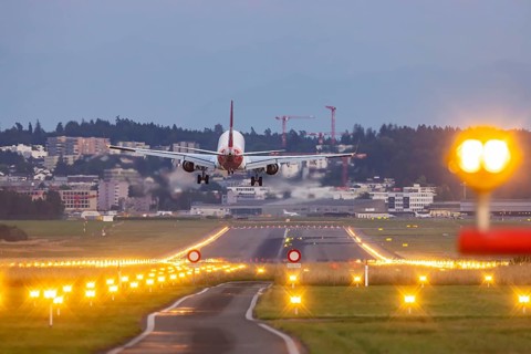 Helvetic Airways aircraft landing in the evening with illuminated runway. Zurich Airport,