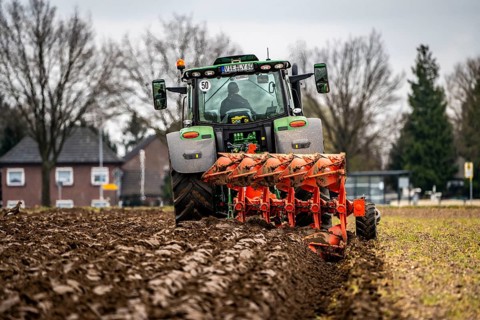 Tractor with a plough preparing the soil of a field for planting, Agriculture, Spring