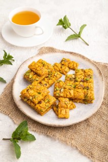 Traditional iranian dessert sohan with cup of green tea on a gray concrete background and linen