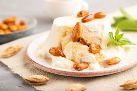Ricotta cheese with honey and almonds on gray concrete background and linen textile. side view,