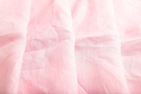Fragment of pink linen tissue. Side view, natural textile background and texture. wave concept,