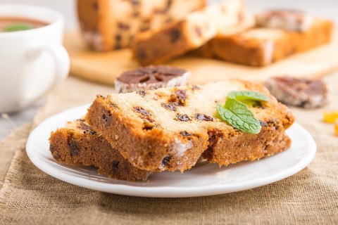 Homemade cake with raisins, dried persimmon and a cup of hot chocolate on a gray concrete