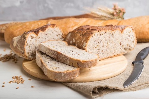Sliced bread with different kinds of fresh baked bread on a white wooden background. side view,
