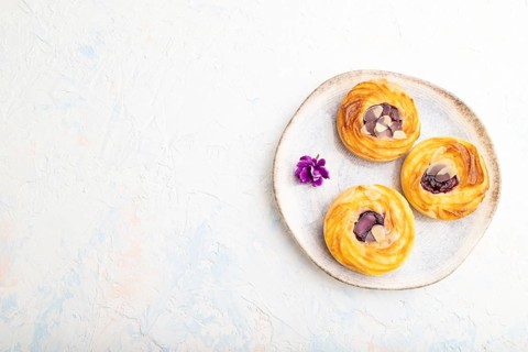Small cheesecakes with jam and almonds with cup of coffee on a white concrete background. top view,