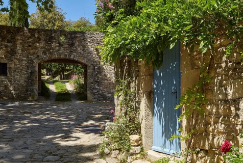Blue entrance door of a house and wall with passageway in La Roque-sur-Cèze, Département Gard,