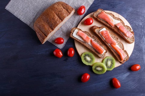 Smoked salmon sandwiches with butter on dark wooden background. cherry tomatoes. top view, copy