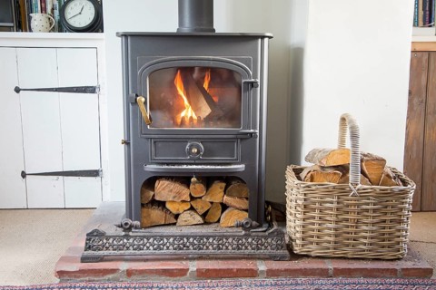Warm fire flames logs burning in ClearView domestic multifuel stove burner inside home, UK