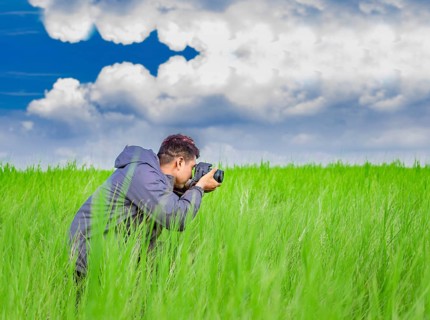 Man taking picture with camera in the field, photographer in the field taking a picture, Latino man