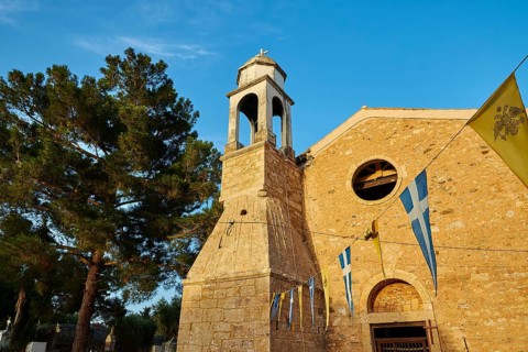 Church bell tower with neighbouring flags and blue sky, Koroni, Byzantine fortress, nunnery,