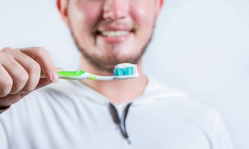 Hand of man showing toothbrush with toothpaste isolated. Close up of hands holding brush with