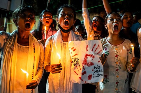 Students holds candle and shout slogans as they participate in a protest against the rape and