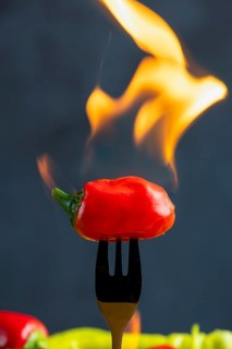 Burning red pepperoni on a fork, close-up, food photography