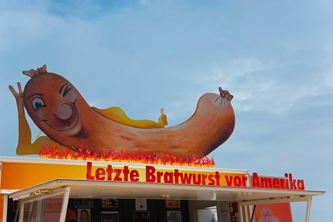 Large sausage with flames on a food truck with humorous lettering, snack bar Last sausage in front