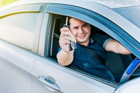 Person in his vehicle showing his car keys, A man in his vehicle showing his new car keys, a happy