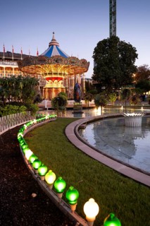 Illuminated historical carousel, garden with pond and lights, dusk, Tivoli Amusement and Recreation