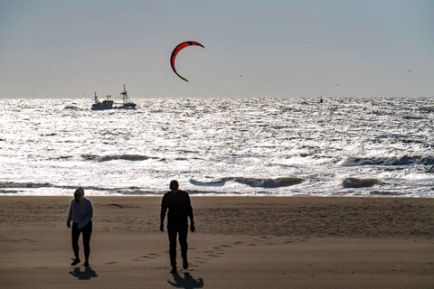 Kitesurfers and shrimp boats off the coast of Scheveningen, walkers on the beach, The Hague,