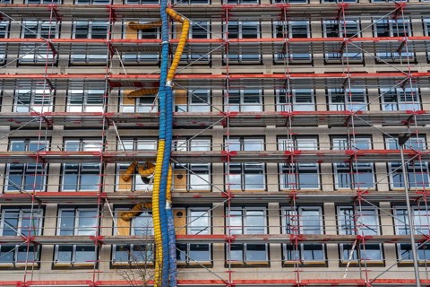 Large construction site, scaffolded shell of an office building complex, air hoses for building