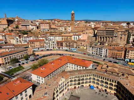 Aerial view of a historic city with many tiled roofs and a striking tower in the centre, aerial