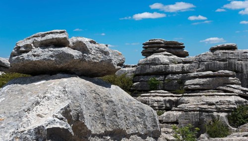 Large boulders under a blue sky with light clouds and scattered vegetation, karst mountains, Torcal