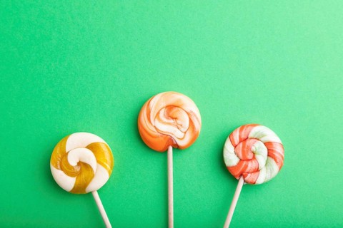 Three lollipop candies on green pastel background. copy space, top view, flat lay