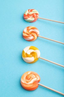 Four lollipop candies on blue pastel background. copy space, side view