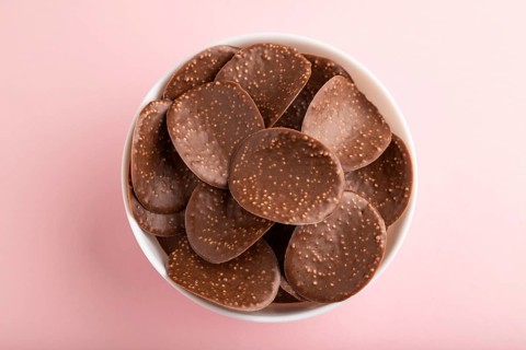Chocolate chips with caramel on pink pastel background. top view, flat lay, close up