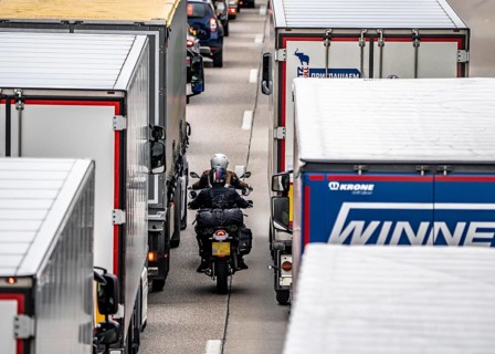 Motorcyclists squeeze past in the middle of the road between vehicles, in a 9 km long traffic jam