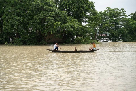 Morigaon, India. 4 July 2024. People travel in a boat to cross a flooded area, in a flood affected