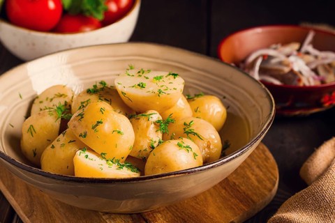 Frisch gekochte, neue Kartoffeln, mit Dill, auf einem Holztisch, selektiver Fokus. Nahaufnahme,