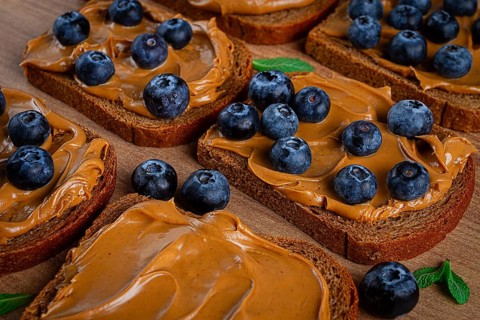 Rye bread with peanut paste and fresh blueberries, top view, no people