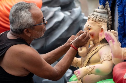 An artisan gives final touches to an idol of the elephant-headed Hindu deity Ganesha at a workshop