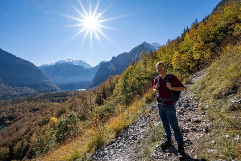 Mountaineers on a mountain hiking trail, Rinnkendlsteig, autumn forest and snow-covered mountains,